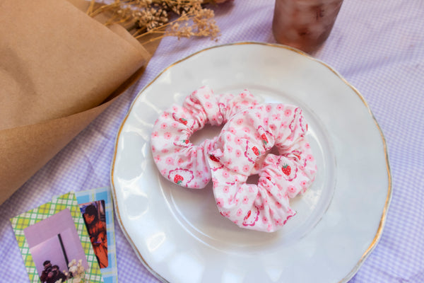 a pink scrunchie with a flower, strawberry, and heart print