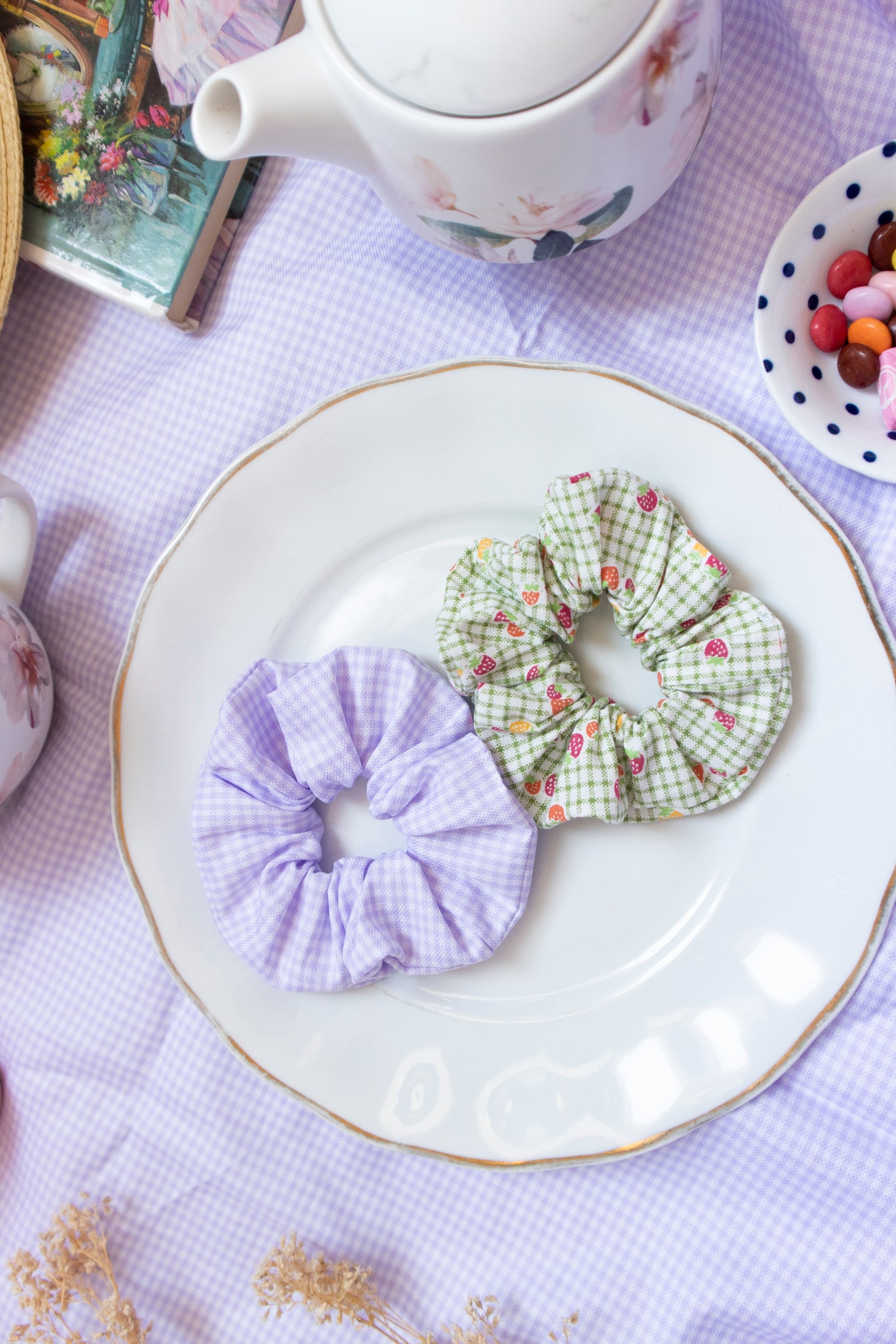 a purple gingham scrunchie and green plaid scrunchie placed on a plate in picnic setting