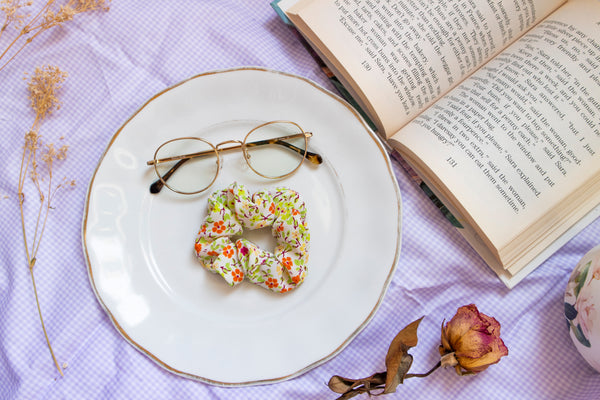 a warm toned scrunchie reminiscent of spring with a green, yellow, orange, and magenta flower print