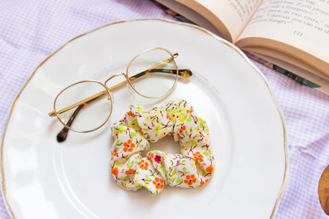 a warm toned scrunchie reminiscent of spring with a green, yellow, orange, and magenta flower print